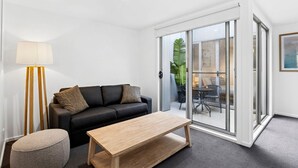 En moderne stue med sofa, sofabord, lampe og en skydedør til et udendørs område.