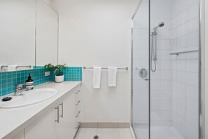 Ein modernes Badezimmer mit einer Duschkabine aus Glas, einem weißen Waschbecken und einem Spiegel.
