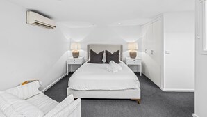 Ein modernes Hotelzimmer mit einem großen Bett, zwei Nachttischen mit Lampen, einem Kleiderschrank und einer Klimaanlage.
