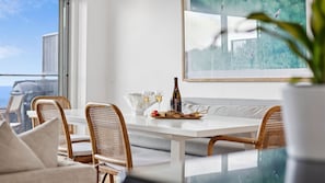 A dining area with wicker chairs, a white table, and a bottle of wine. - Oceanview on Mountjoy (Lorne)