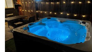 Un jacuzzi con luz azul, rodeado de paredes de madera y luces colgantes.