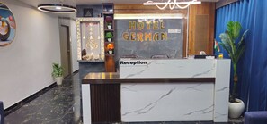 A hotel reception desk with a marble top, a reception area, and a wall with the hotel name 'HOTEL GERMAN'. - HOTEL GERMAN (Gandhinagar)