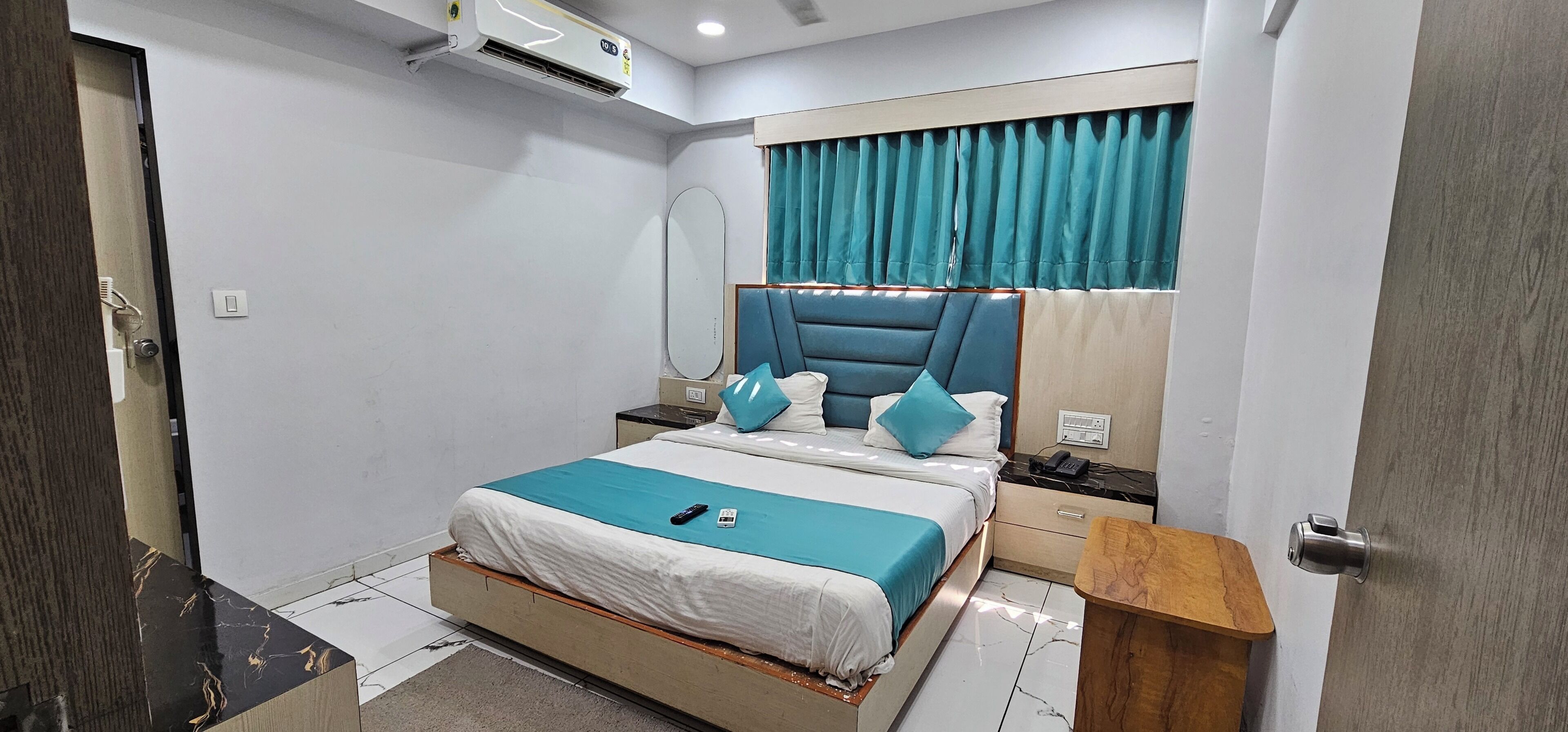 A modern bedroom with a bed, bedside tables, a mirror, and a window with curtains.