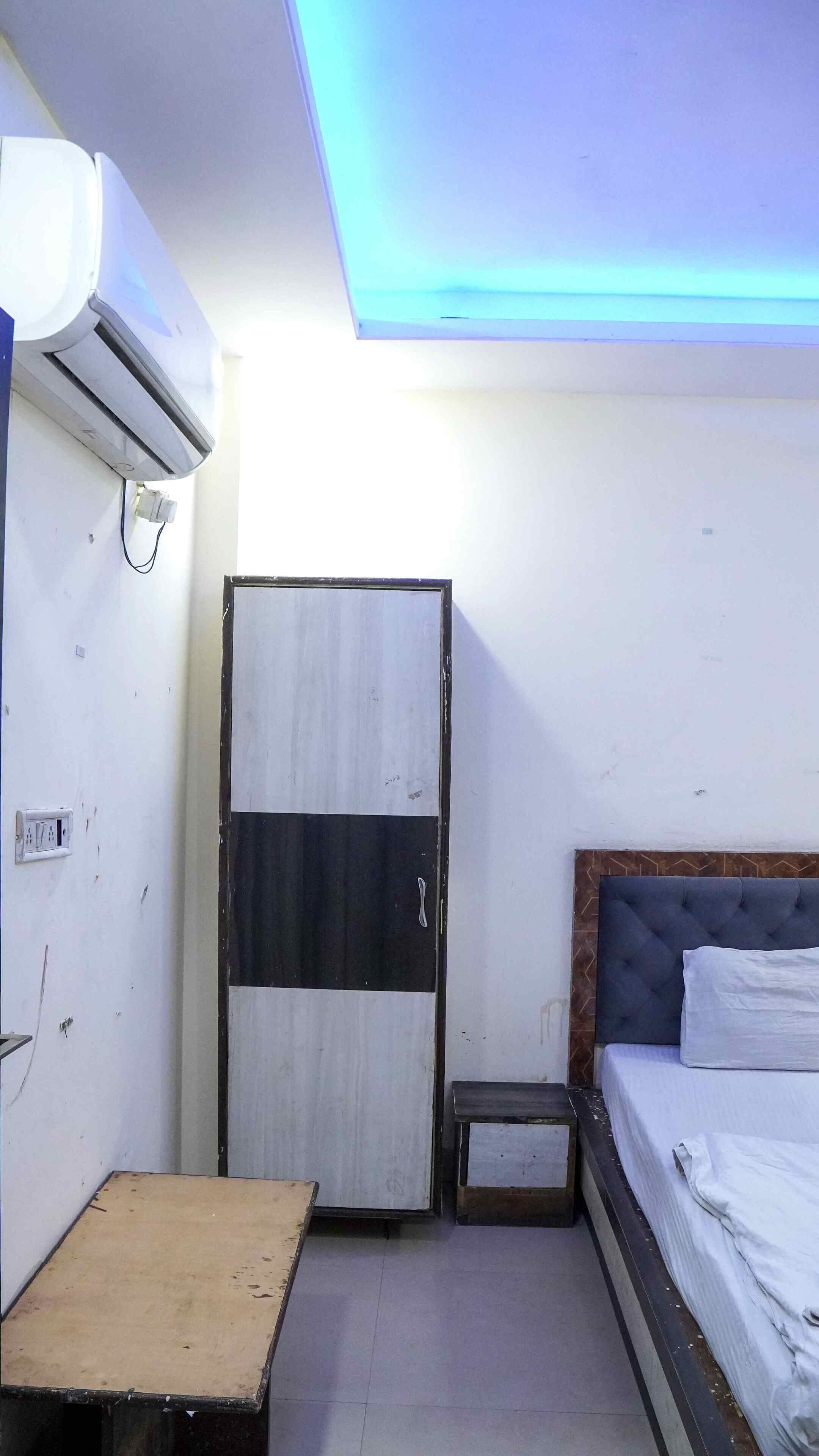 A small, compact room with a bed, a wardrobe, and a small table.