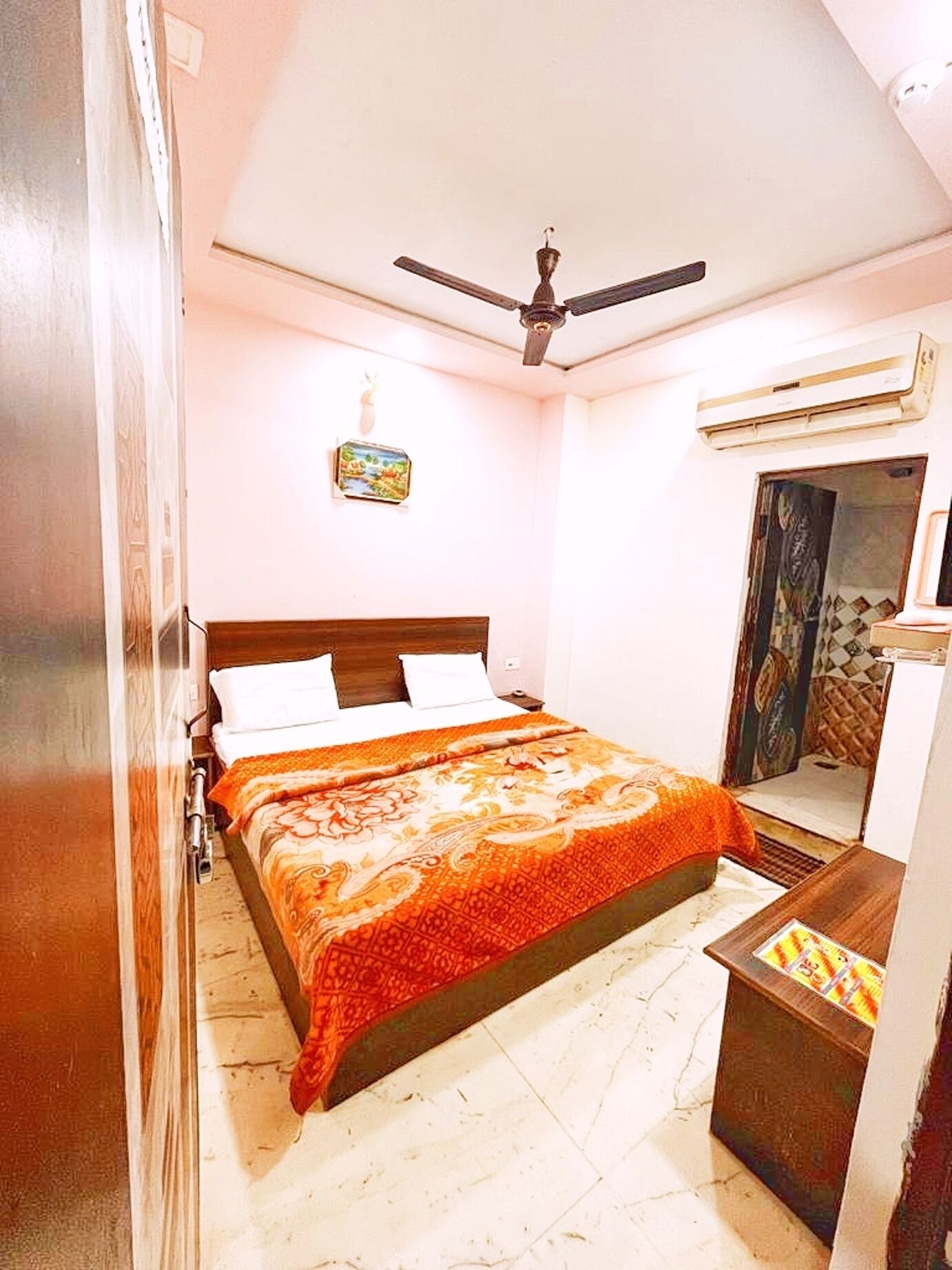 Une chambre à coucher comprenant un lit, un ventilateur de plafond, un appareil de climatisation, une petite table et un miroir.