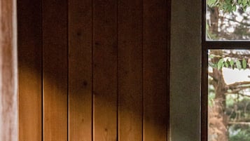 A person lying on a bed in a room with wooden walls and a window.