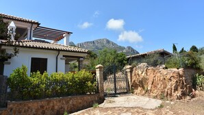 A villa with a tiled roof, stone walls, and a view of mountains.