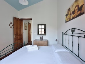 A bedroom with a bed, a wooden dresser, a desk, a window, and a painting on the wall. - Apartmento a 3-minute walk from the beach. (Santa Maria Navarrese)