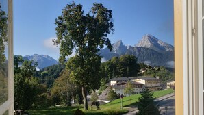 Vista da janela com paisagem montanhosa, estrada e edifícios ao primeiro plano.