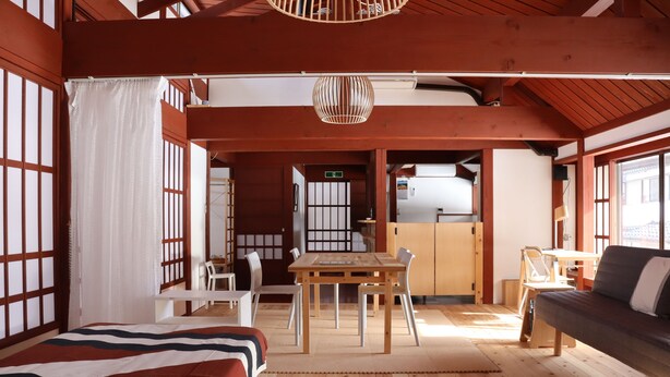 A traditional Japanese-style room with tatami flooring, a low wooden table, and a sofa.