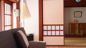 A room with a wooden floor, a sofa, a lamp, and a sliding door.