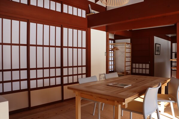 A traditional Japanese room with tatami flooring, a wooden table, and white chairs.