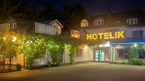 Hotelli nimeltä ”HOTELIK”, jossa on kivetty sisäpiha, kyltti ja parvekkeellinen rakennus.
