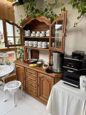 A kitchen with wooden cabinets, a coffee machine, and a white table with a white tablecloth. - Hotelik Zielonka (Zielonka)