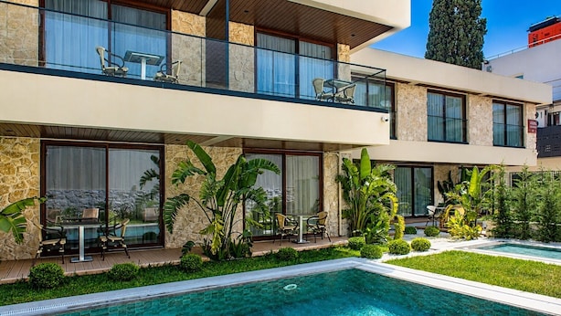 A modern two-story house with a swimming pool, stone walls, and tropical plants. - ARKK ROOMS (Antalya)