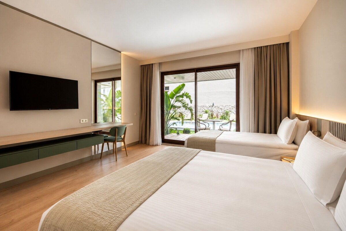 Una camera d'albergo con un letto, una scrivania, una televisione e un balcone con vista.