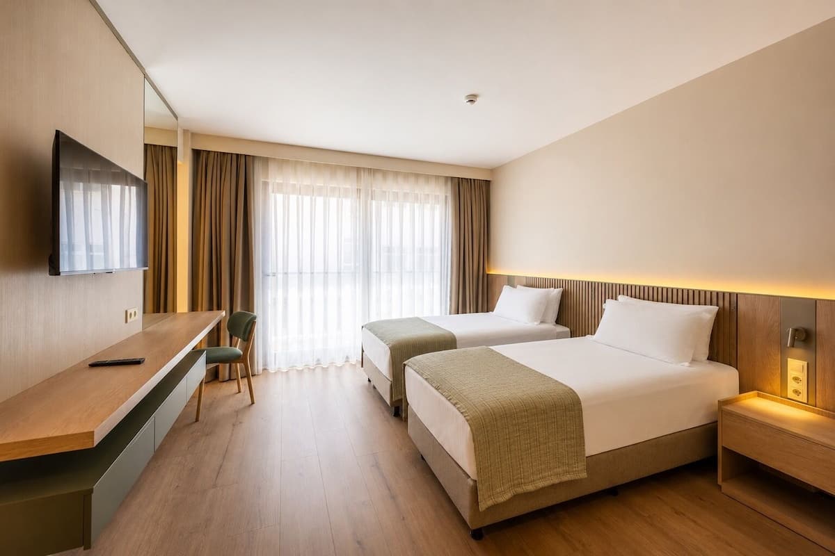 Une chambre d’hôtel avec deux lits, un bureau, une chaise et un téléviseur.