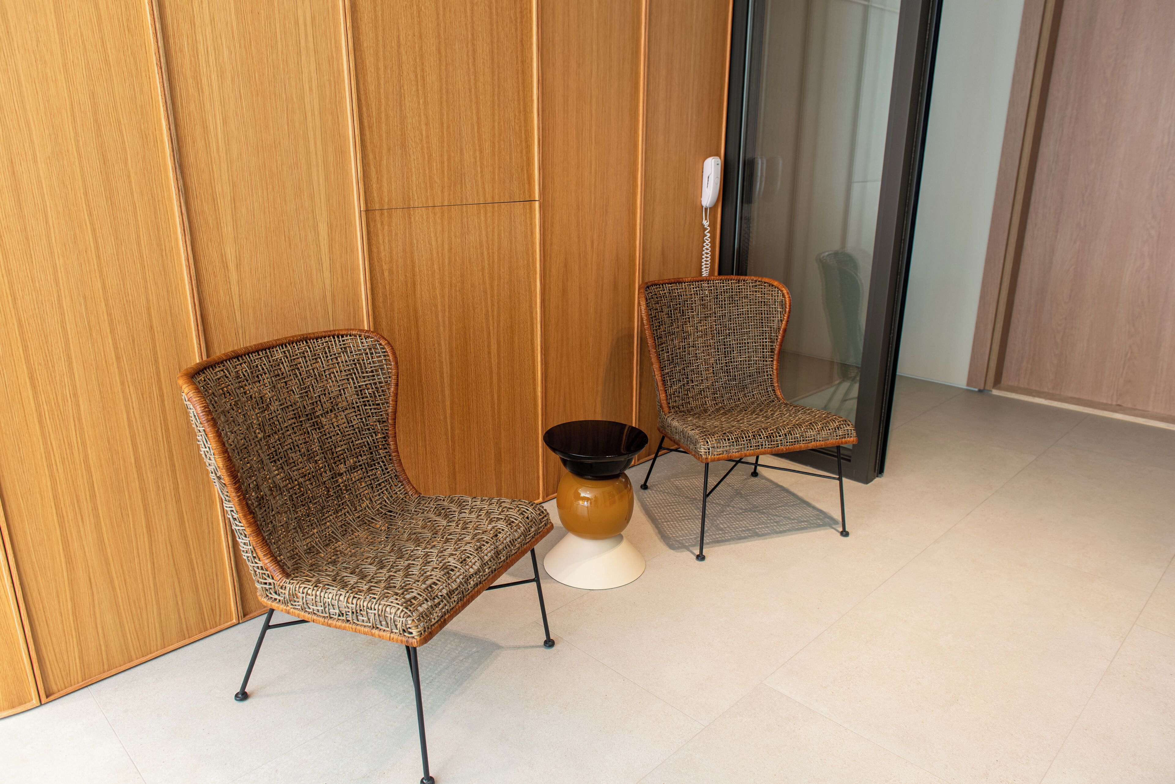 Two wicker chairs with metal legs and a small round table with a black bowl.