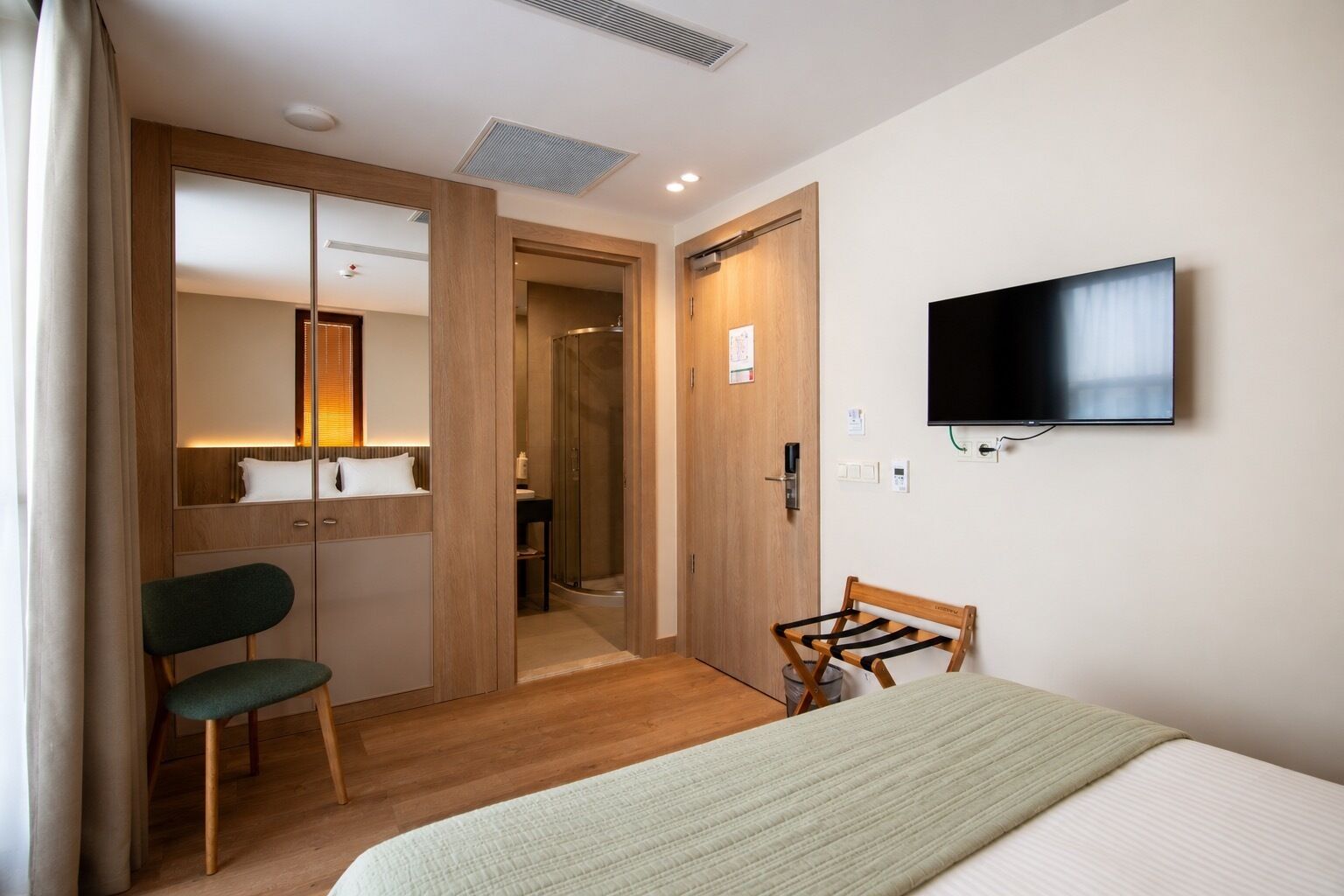 Une chambre d’hôtel équipée d’un lit, d’une télévision, d’une armoire en bois, d’un miroir et d’une douche.