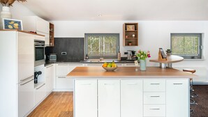 Una cucina moderna con mobili bianchi, un piano di lavoro in legno e una ciotola di frutta.