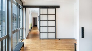 Un corridoio con pavimento in legno, ampie finestre e una porta scorrevole.