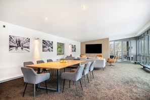Ein modernes Interieur mit Konferenztisch, grauen Stühlen, einer Couch und einem Fernseher.