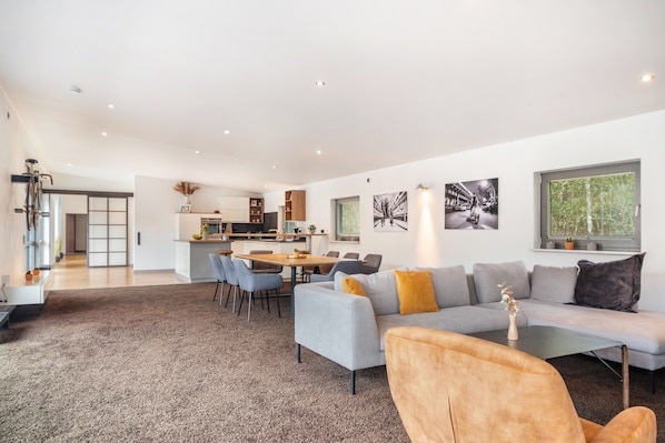 Ein modernes Wohnzimmer mit Sofa, Sesseln und einem Essbereich.
