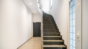 A modern interior with a curved staircase leading to a dark door. - Apartment 'Moselbude Kröv' with Moselle View, Sauna, Terrace, E-Bikes Included, Grill (Kröv)