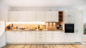 A modern kitchen with white cabinets, a wooden countertop, and a built-in oven. - Apartment 'Moselbude Kröv' with Moselle View, Sauna, Terrace, E-Bikes Included, Grill (Kröv)