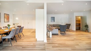 A modern interior with a dining area, a sofa, and a wooden floor. - Apartment 'Moselbude Kröv' with Moselle View, Sauna, Terrace, E-Bikes Included, Grill (Kröv)
