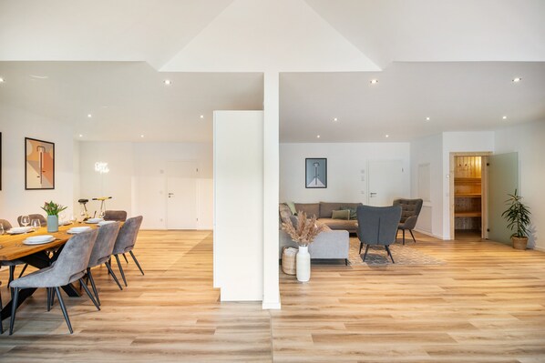 Un interior moderno con comedor, sofá y suelo de madera.