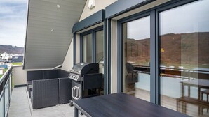 A balcony with a grill, outdoor seating, and large windows. - Apartment 'Moselbude Kröv' with Moselle View, Sauna, Terrace, E-Bikes Included, Grill (Kröv)