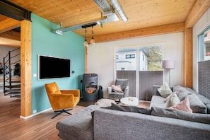 Un salon moderne doté d’un téléviseur à écran plat, d’un canapé, d’un fauteuil, d’une cheminée et d’un escalier menant à un autre niveau.