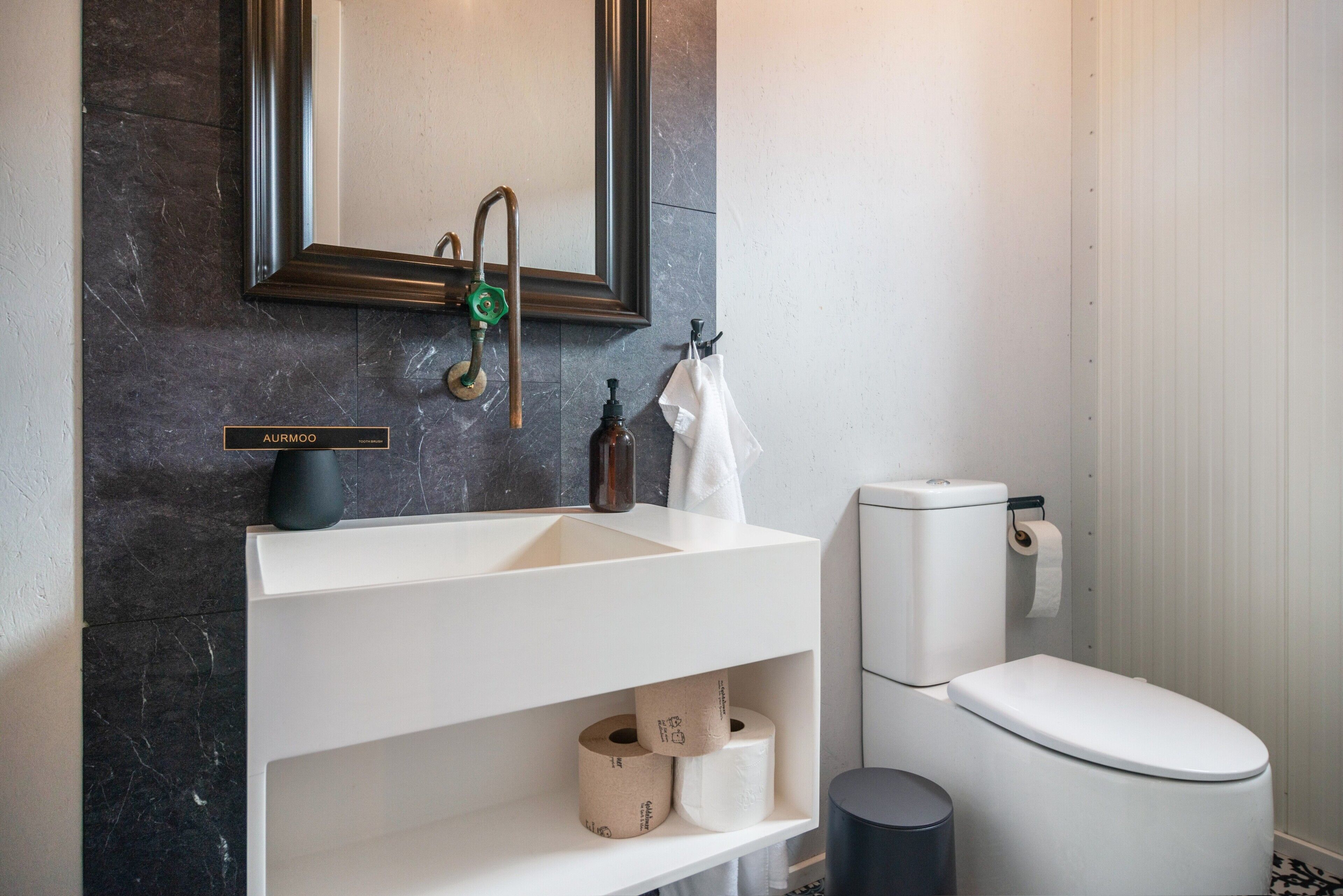 Un bagno moderno con un lavandino bianco, un water e uno specchio sopra il lavandino.