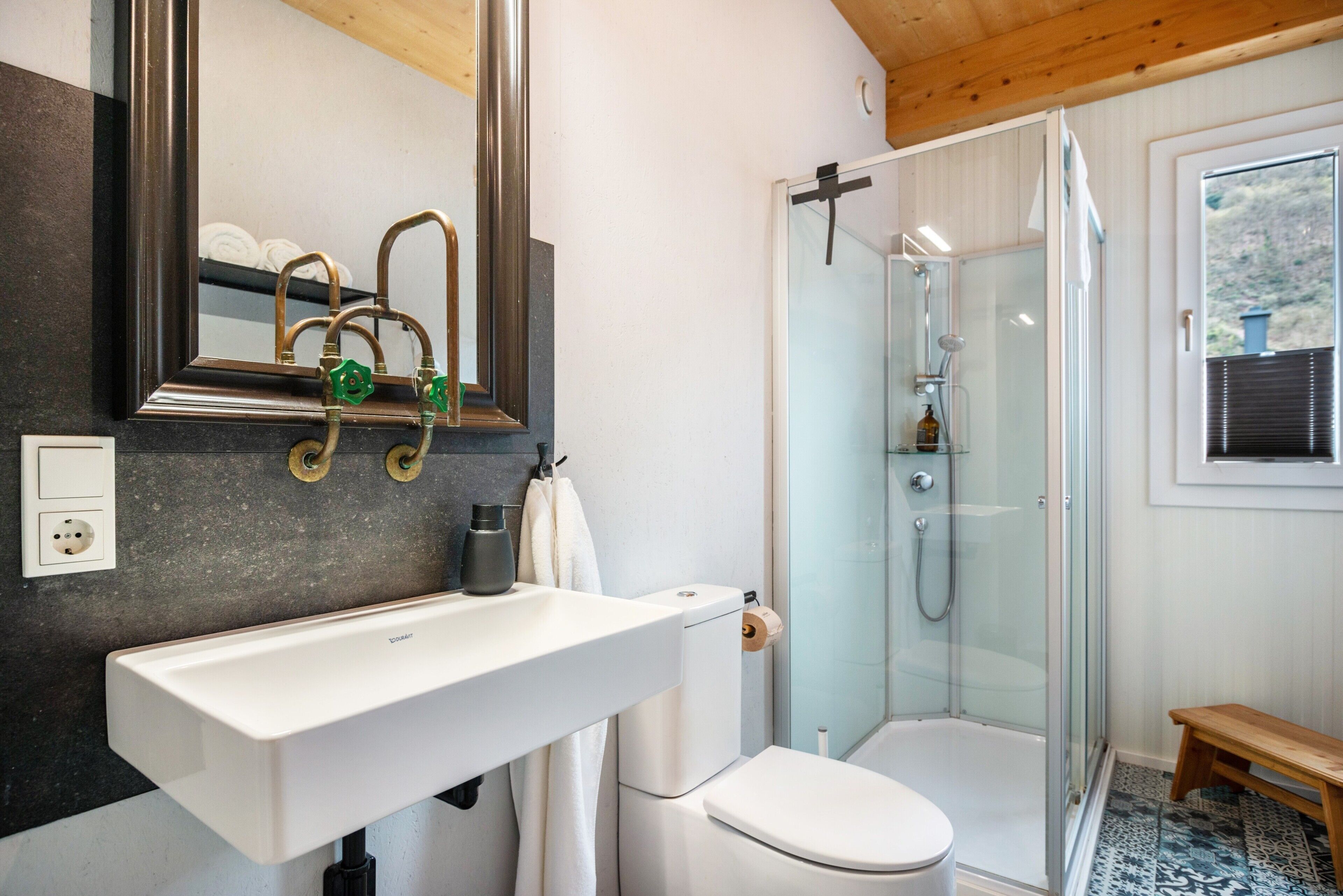 Une salle de bain avec un lavabo blanc, des toilettes et une douche fermée par des parois en verre.