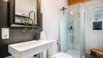 Une salle de bain avec un lavabo blanc, des toilettes et une douche fermée par des parois en verre.