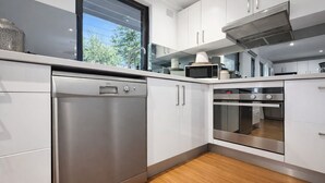 Una cocina moderna con electrodomésticos de acero inoxidable, armarios blancos y piso de madera.