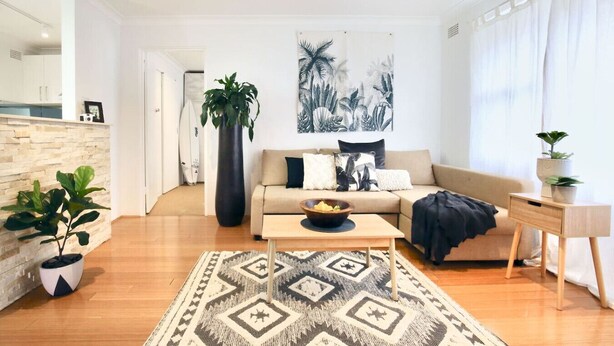 Una sala de estar moderna con un sofá, una mesa de centro y una planta grande.