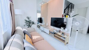 A modern living room with a sofa, TV, and fan.