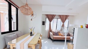 A modern living space with a dining area, sofa, and a fan.