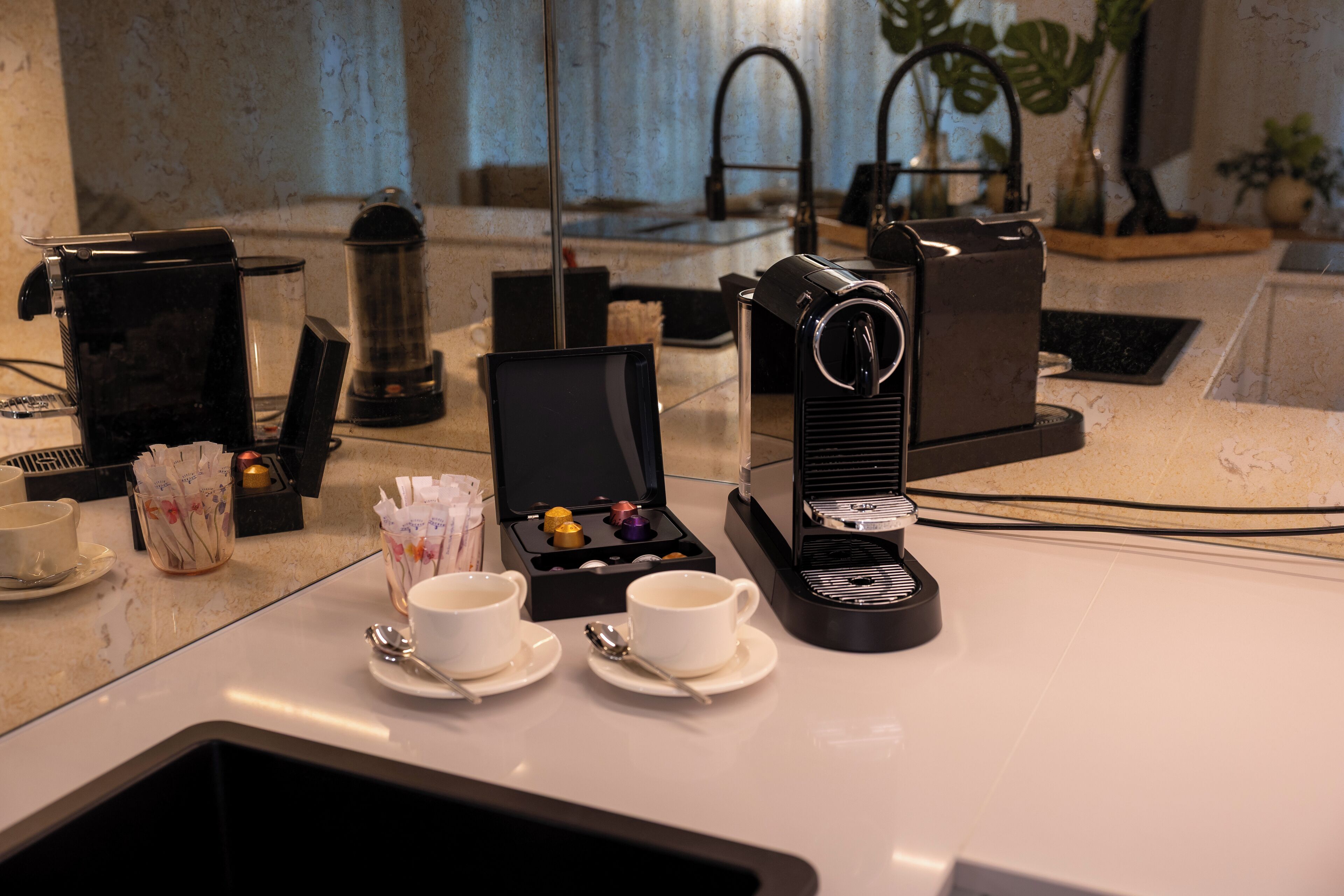 Eine Kaffeestation mit Kaffeemaschine, Tassen und einer Schachtel Pralinen.