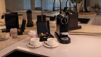 Eine Kaffeestation mit Kaffeemaschine, Tassen und einer Schachtel Pralinen.