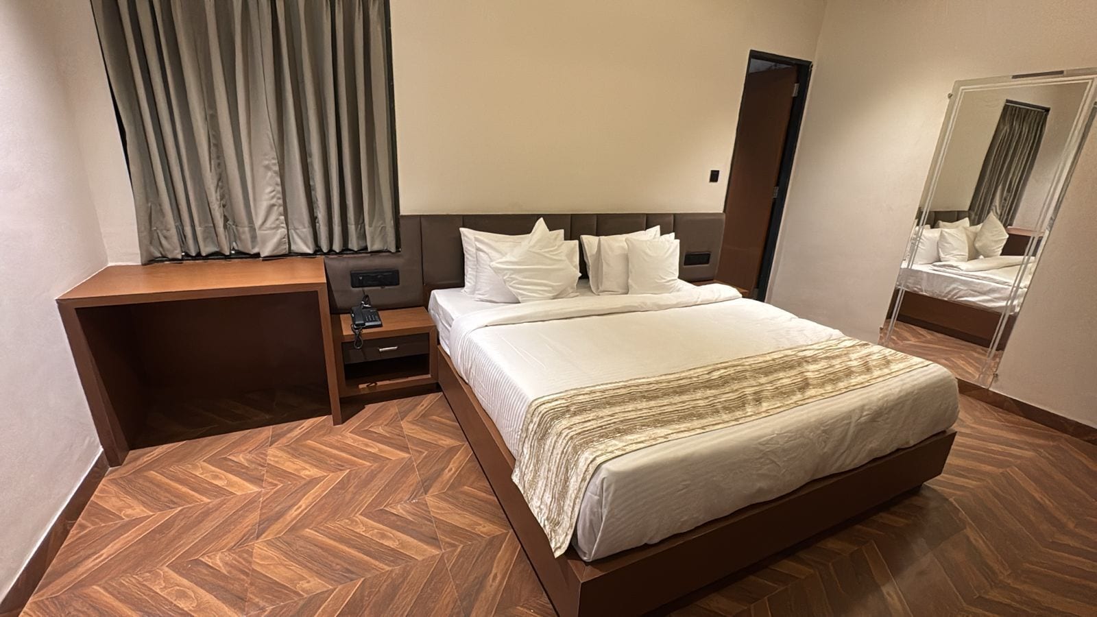Una habitación de hotel con cama, mesita de noche y espejo.