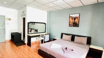 A hotel room with a bed, a desk, a chair, a mirror, and a picture on the wall.