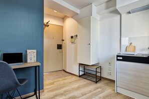 Eine kompakte Küche mit modernem Design, inklusive eines eingebauten Geschirrspülers, einem kleinen Tisch mit einem Laptop und einem Stuhl.