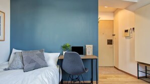 A bedroom with a bed, a desk, and a chair. There is a door in the background. - Modern Living Tokyo Komagome 508, a compact studio at excellent location (豊島区 駒込)