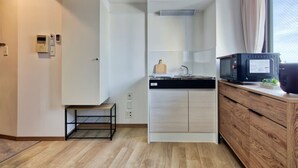 A compact kitchen with a microwave, a small sink, and a wooden cabinet. - Modern Living Tokyo Komagome 508, a compact studio at excellent location (豊島区 駒込)