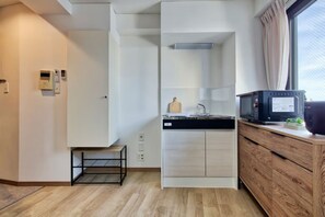 Eine kleine Küche mit Mikrowelle, Spüle und Holzschrank.