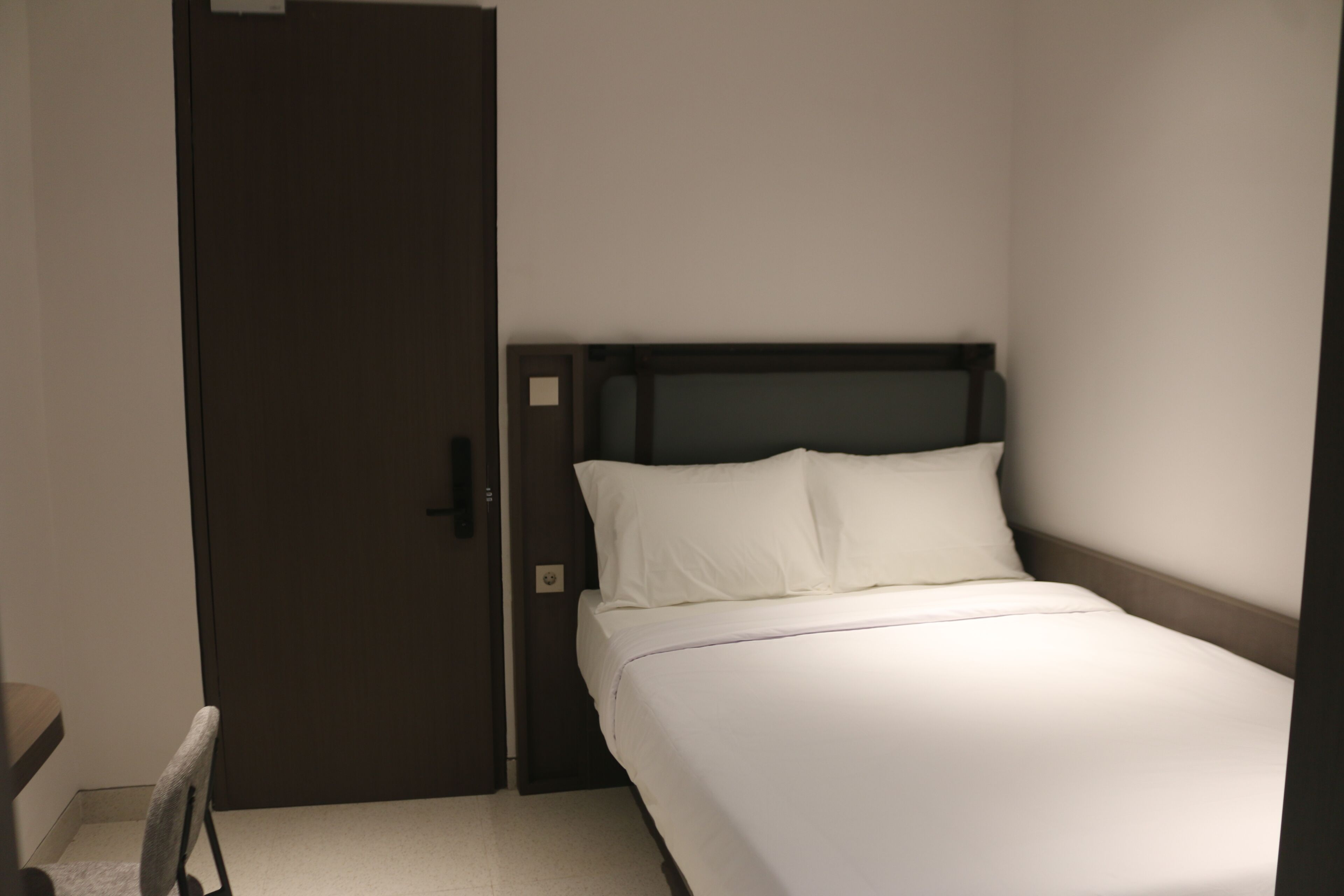 Een hotelkamer met een bed, een deur en een stoel.