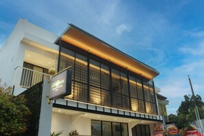 A modern hotel with a large glass facade, a balcony, and a sign indicating it is a 'Serenity House.' - The Hanoman Serenity House by Sajiwa (Surakarta)
